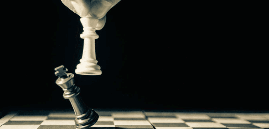 An empty chessboard other than two pieces - one piece is knocking the other over.