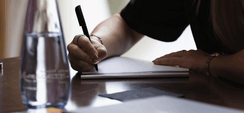 A person writing in a notebook with a pen.

screenplay opening scene