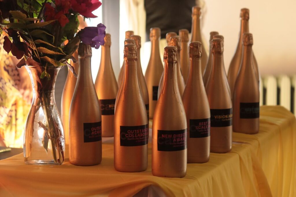 A table of champagne bottles that serve as awards at the Catalyst Institute for Creative Arts and Technology's annual end of year awards show: The Catties. Awards include Screenwriting, outstanding collaboration, vision award, and more.
