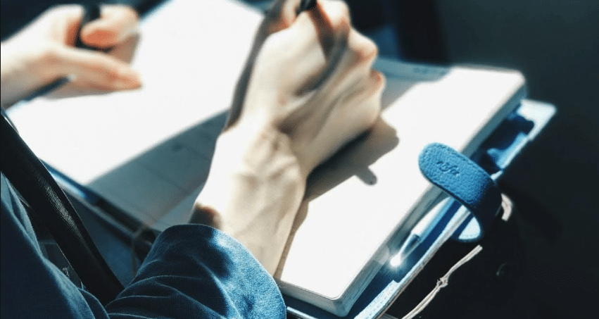 Photo of a person writing in a notebook or journal
