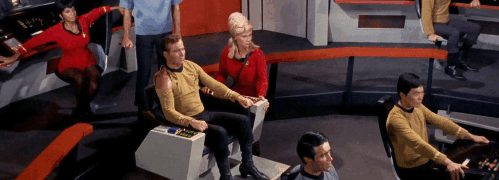 The cast of Star Trek (the original series) sits in the bridge of the Enterprise