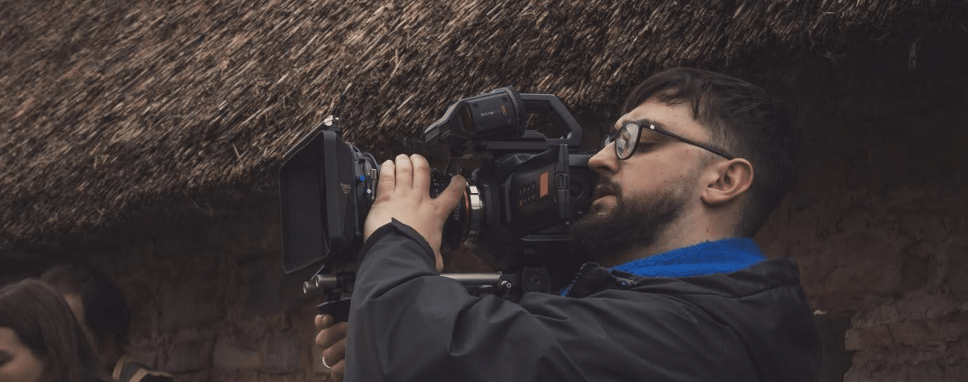 A man holding a film camera on his shoulder