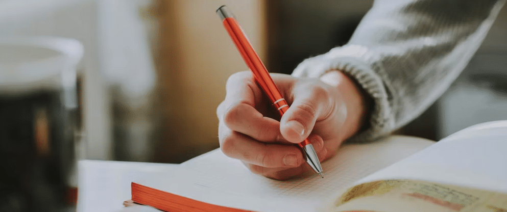Character development.

A photo of a person with a pen in their hand writing in a notebook