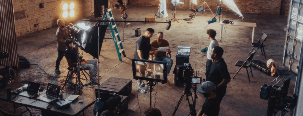 a production crew milling around a film set in a warehouse