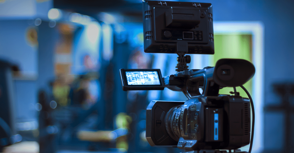 A black camera on a tripod, used for filming a production with a documentary treatment