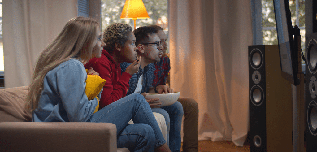 a group of people intently watching a movie so they can do a film analysis later.