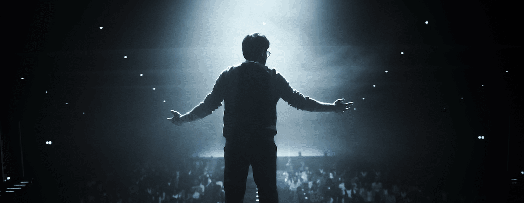 a man on stage delivering a soliloquy in front of an audience.