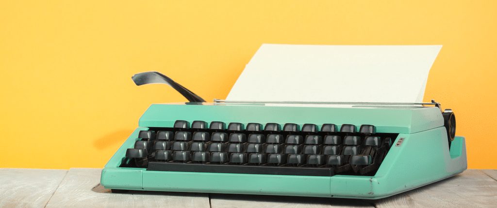 a vintage teal typewriter against a yellow background.